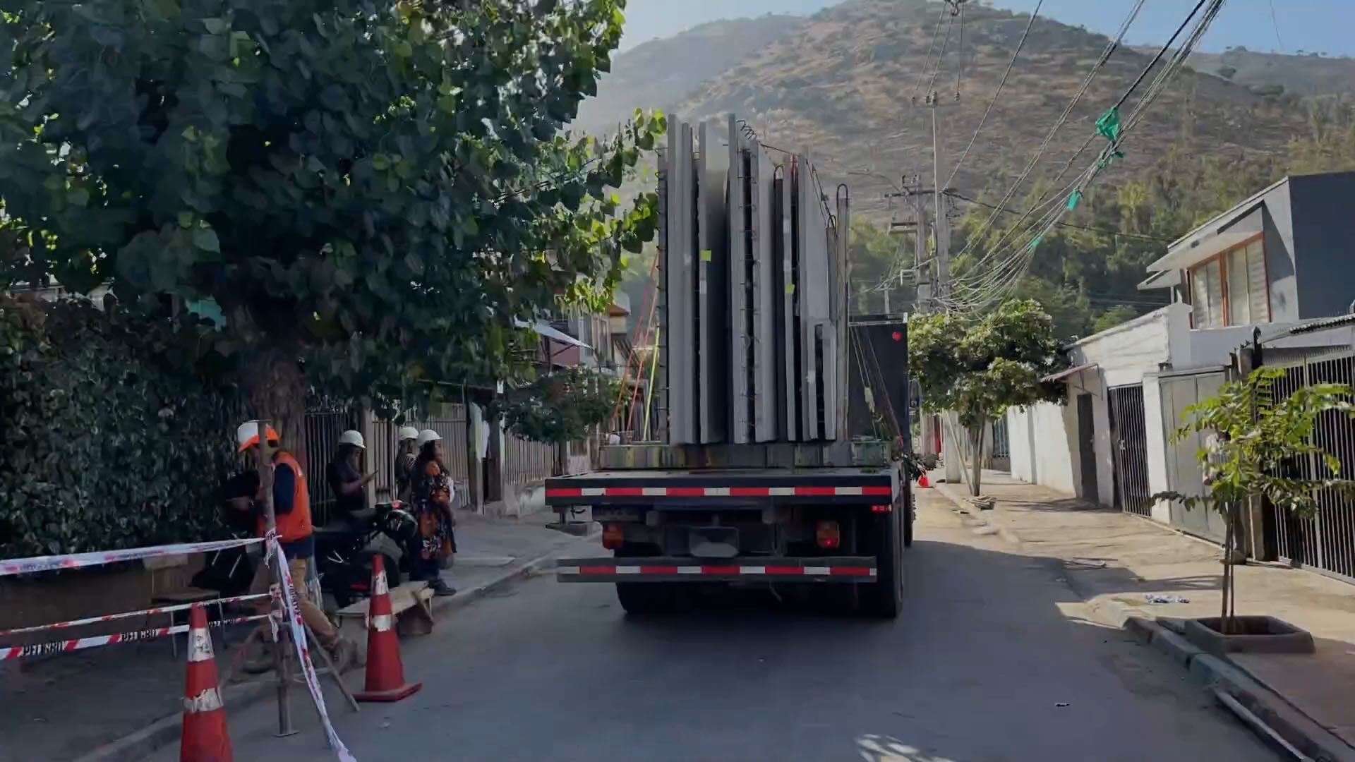 Camión de alto tonelaje transportando paneles de hormigón en pasaje residencial estrecho